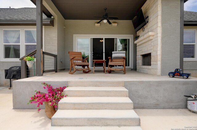 view of patio / terrace featuring a large fireplace, ceiling fan, and covered porch