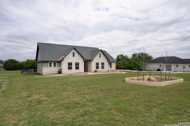 view of front facade featuring a front lawn, stone siding, and roof with shingles