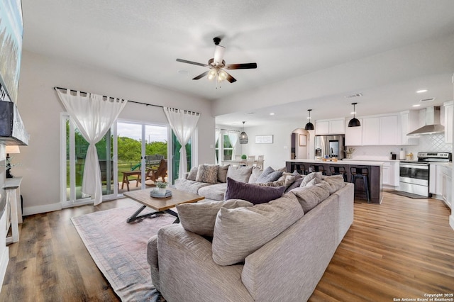 living area featuring light wood-type flooring, a ceiling fan, visible vents, recessed lighting, and baseboards