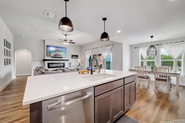 kitchen with a glass covered fireplace, visible vents, ceiling fan, stainless steel dishwasher, and a sink