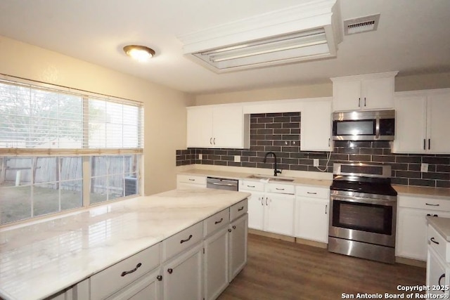 kitchen with tasteful backsplash, visible vents, a sink, appliances with stainless steel finishes, and white cabinetry