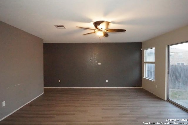 spare room featuring visible vents, a wealth of natural light, a ceiling fan, and wood finished floors