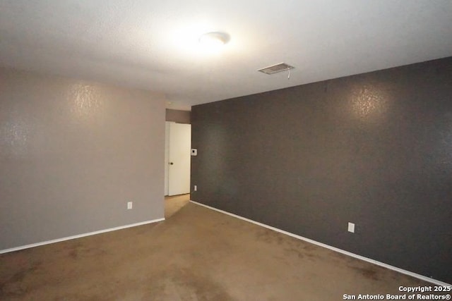 carpeted spare room with baseboards and visible vents