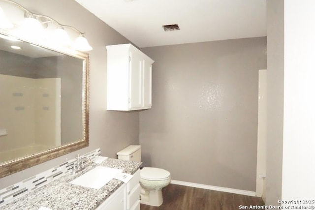 bathroom with vanity, baseboards, toilet, visible vents, and wood finished floors