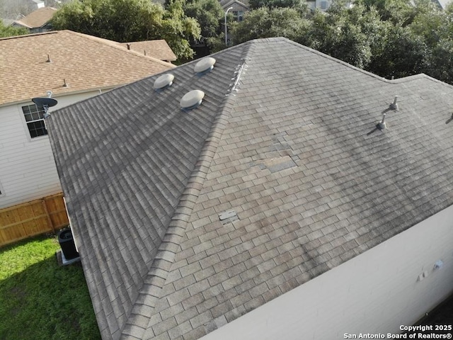 details featuring fence and a shingled roof