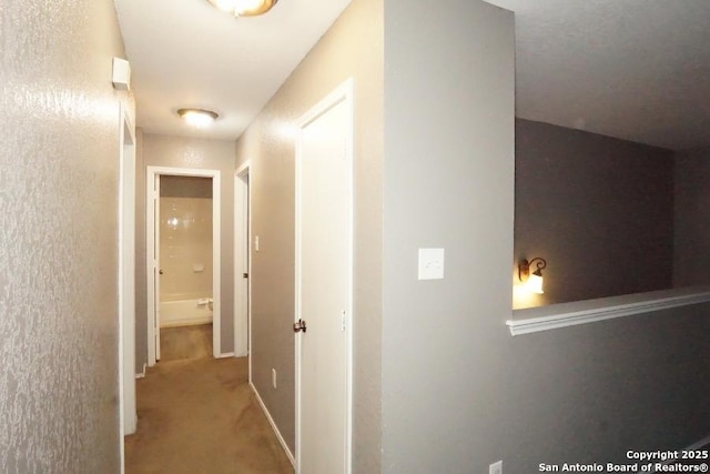 corridor featuring baseboards and carpet floors