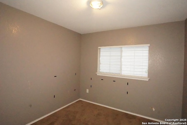carpeted spare room featuring baseboards