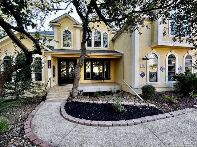 view of front facade featuring a porch, french doors, and stucco siding
