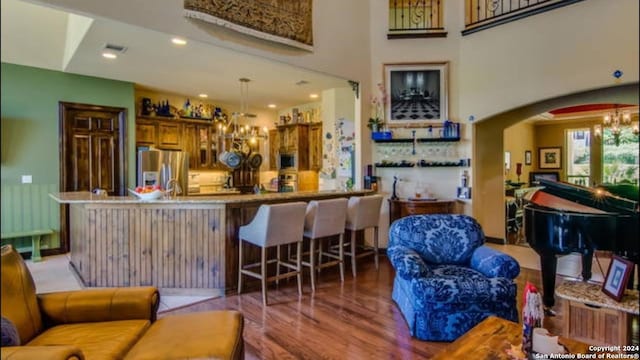 bar with hanging light fixtures, arched walkways, a chandelier, stainless steel appliances, and wood finished floors