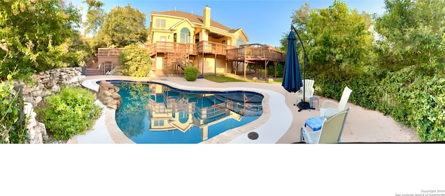 outdoor pool featuring a wooden deck, stairs, and a patio area