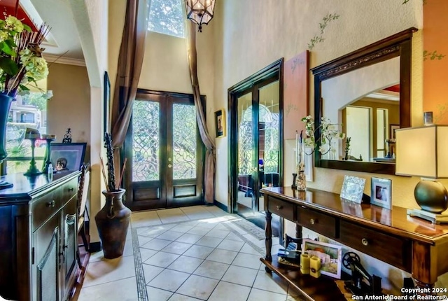 foyer entrance with french doors, ornamental molding, tile patterned floors, and a healthy amount of sunlight