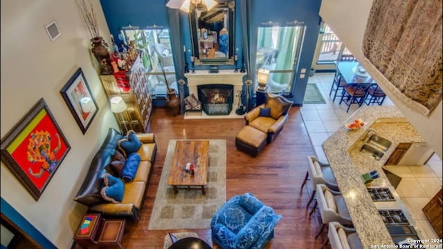 living room with a lit fireplace, a high ceiling, visible vents, and wood finished floors