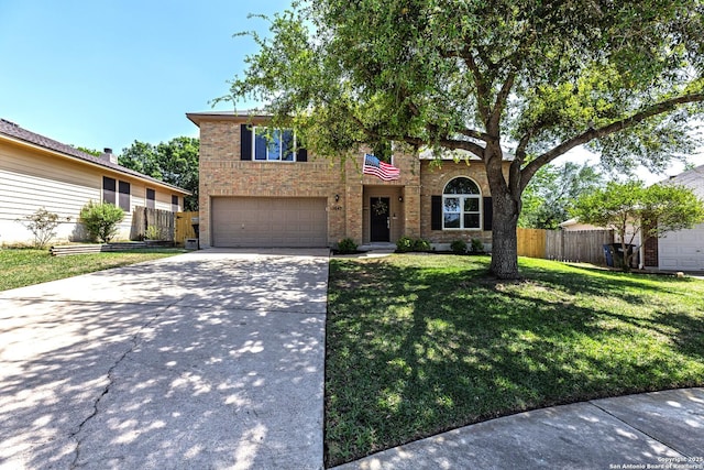 traditional-style home featuring a front lawn, driveway, fence, brick siding, and an attached garage