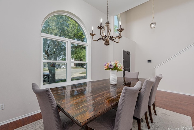 dining room featuring plenty of natural light, baseboards, wood finished floors, and an inviting chandelier