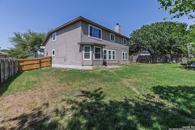 rear view of house with a lawn, a fenced backyard, and a chimney