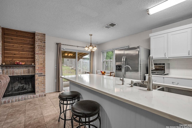 5906 Kissing Oak, San Antonio, TX 78247 - kitchen featuring a sink, visible vents, white cabinetry, stainless steel refrigerator with ice dispenser, and a breakfast bar area