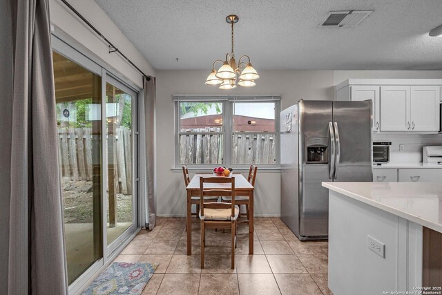 5906 Kissing Oak, San Antonio, TX 78247 - kitchen with an inviting chandelier, light countertops, visible vents, stainless steel fridge, and a textured ceiling