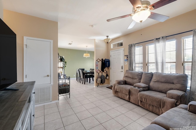 living room with baseboards, a ceiling fan, visible vents, and light tile patterned floors