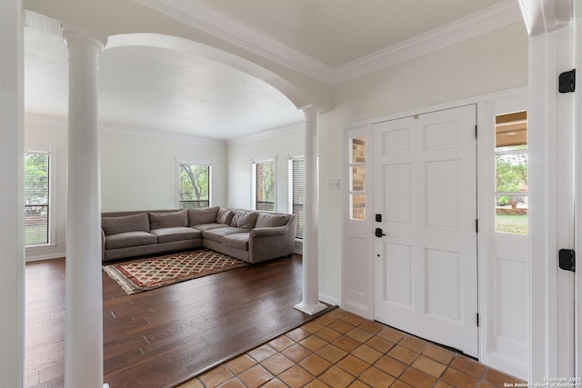 foyer featuring tile patterned floors, arched walkways, ornate columns, and crown molding