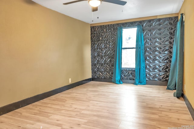 spare room featuring ceiling fan, baseboards, and wood finished floors