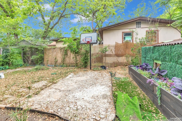 view of yard featuring fence and basketball court