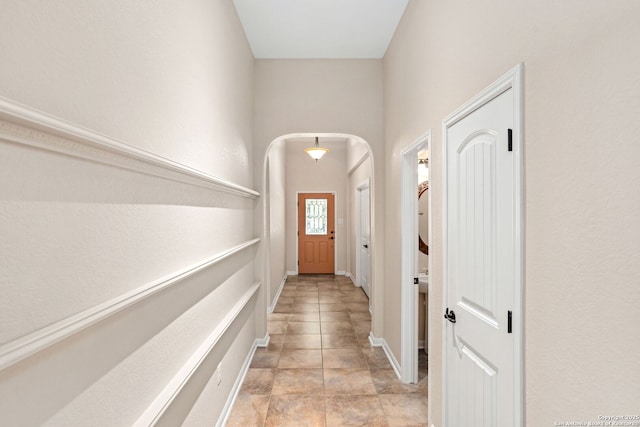 doorway with arched walkways and baseboards