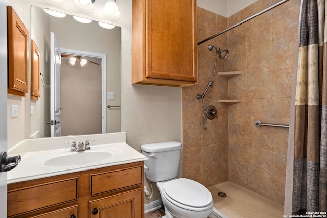 bathroom with a tile shower, toilet, and vanity