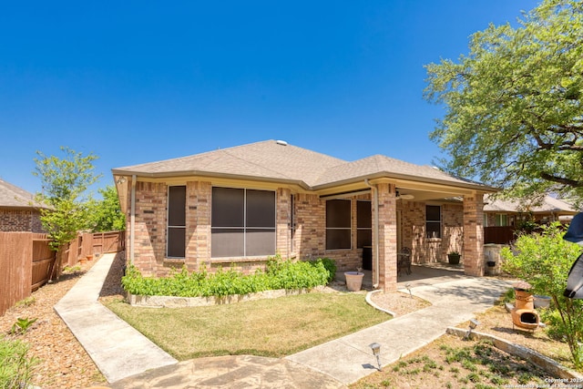 back of property featuring a patio area, a lawn, a shingled roof, fence, and brick siding