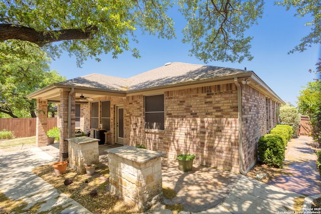 rear view of house with brick siding, fence, a patio, and ceiling fan