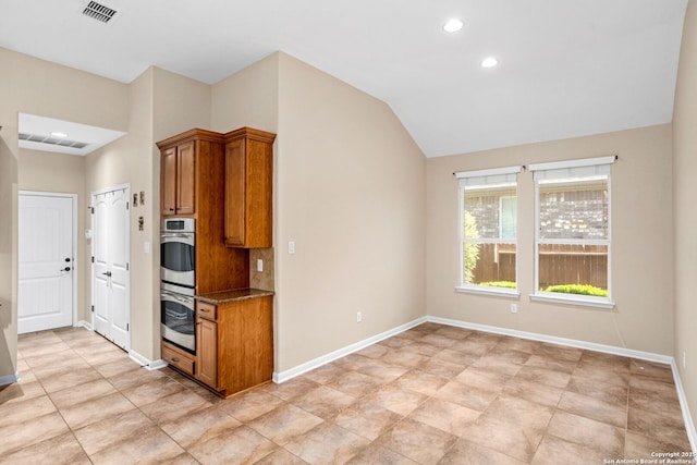 kitchen featuring brown cabinets, visible vents, baseboards, and dark stone countertops