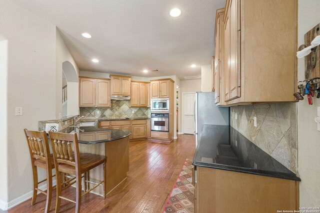 3329 Navasota Cir, San Antonio, TX 78259 - kitchen featuring appliances with stainless steel finishes, under cabinet range hood, a kitchen breakfast bar, a peninsula, and light wood-type flooring