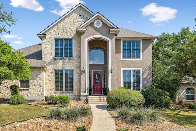 traditional-style home with roof with shingles, stone siding, and stucco siding