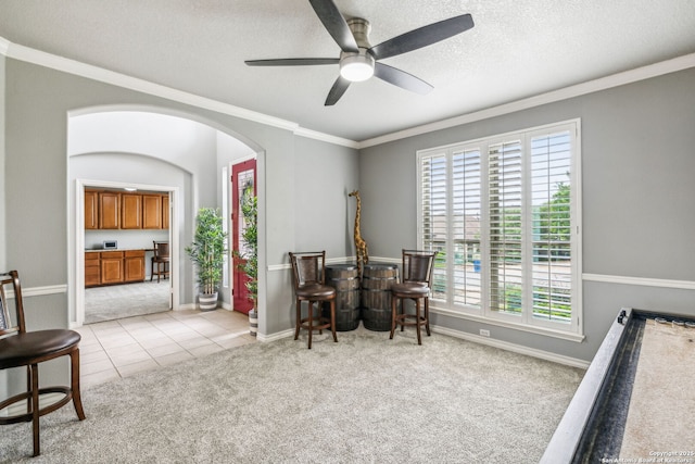 sitting room with ornamental molding, arched walkways, a textured ceiling, light colored carpet, and ceiling fan