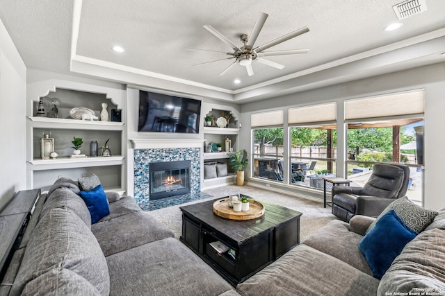carpeted living room with a fireplace, a ceiling fan, visible vents, and plenty of natural light