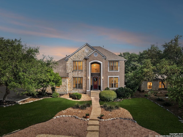 traditional home featuring a lawn and stone siding