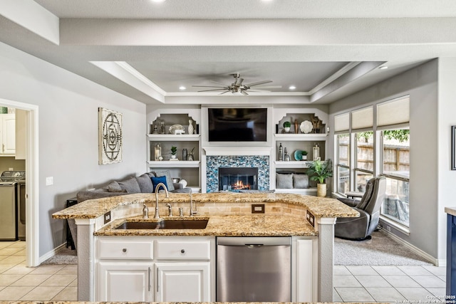 kitchen featuring washing machine and dryer, stainless steel dishwasher, a sink, and light tile patterned floors