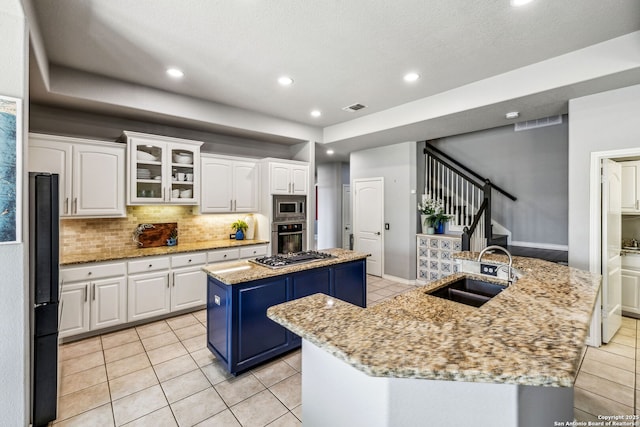 kitchen with appliances with stainless steel finishes, a sink, a kitchen island with sink, and light tile patterned floors