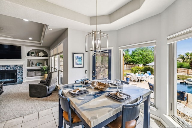 dining room featuring a tray ceiling, a wealth of natural light, built in features, and a notable chandelier