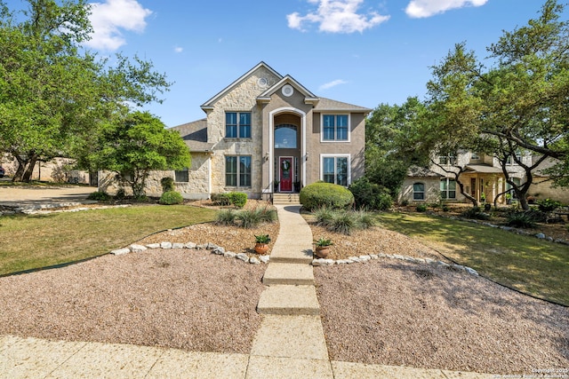 traditional-style home featuring stone siding, a front yard, and stucco siding