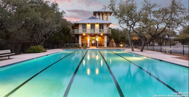 pool at dusk featuring a fenced in pool and fence