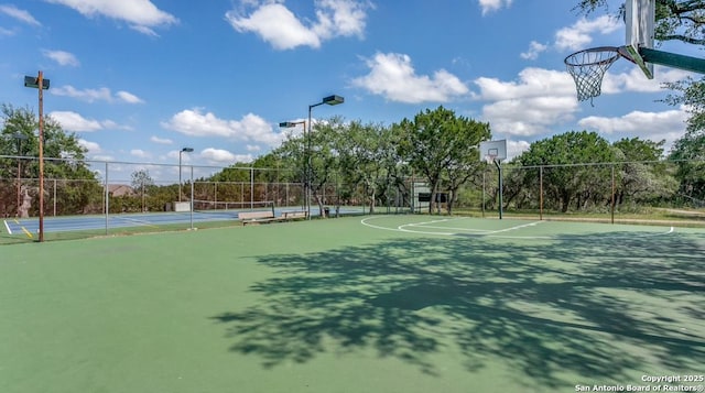 view of basketball court featuring community basketball court, a tennis court, and fence