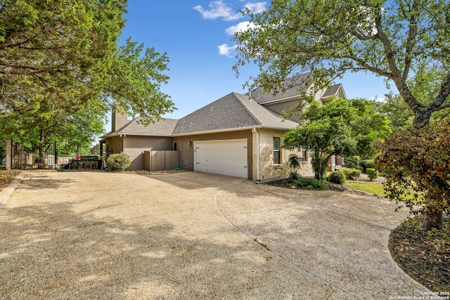 view of home's exterior with fence, stucco siding, driveway, roof with shingles, and a garage