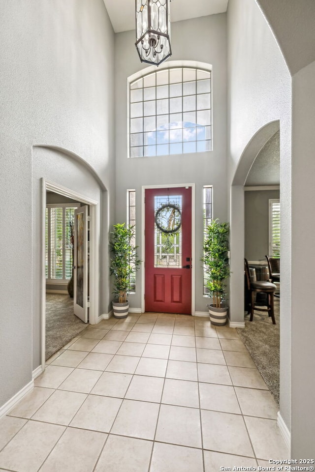 entryway featuring a wealth of natural light, a high ceiling, arched walkways, and a chandelier