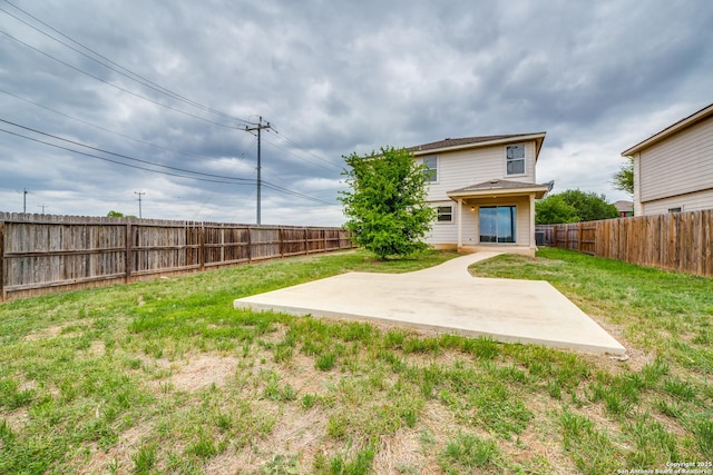 rear view of house featuring a fenced backyard, a yard, and a patio area