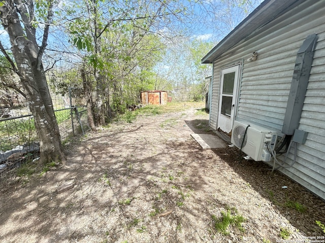 view of yard with an outdoor structure, fence, ac unit, and a storage shed
