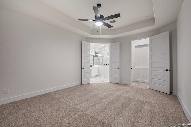 unfurnished bedroom featuring baseboards, visible vents, carpet, and a raised ceiling