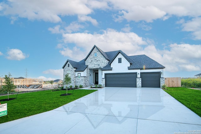view of front of property with a garage, stone siding, a front yard, and concrete driveway