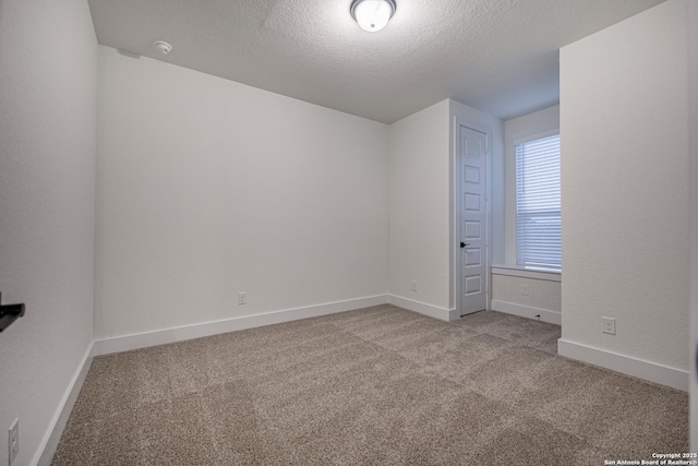 empty room featuring a textured ceiling, carpet flooring, and baseboards