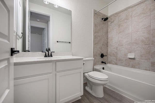 full bathroom with toilet, shower / bath combination, wood finished floors, a textured wall, and vanity