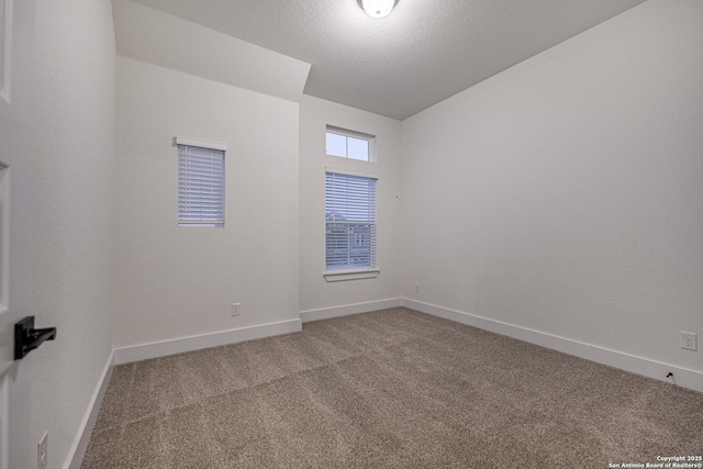 carpeted empty room featuring a textured ceiling and baseboards